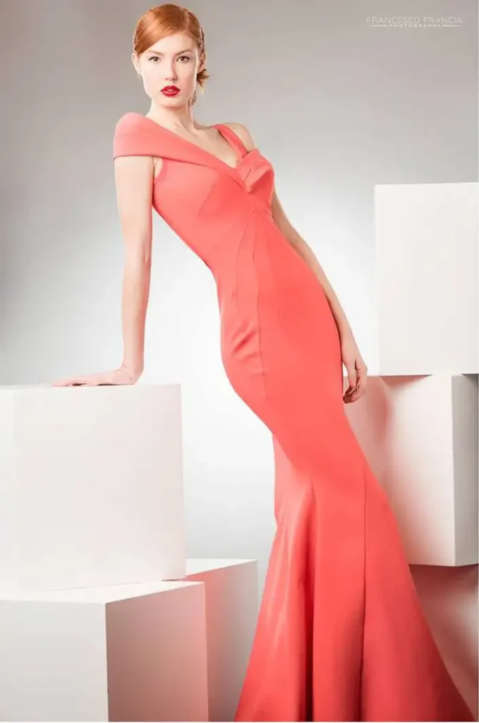 Modella in abito lungo rosso in posa su cubi bianchi.