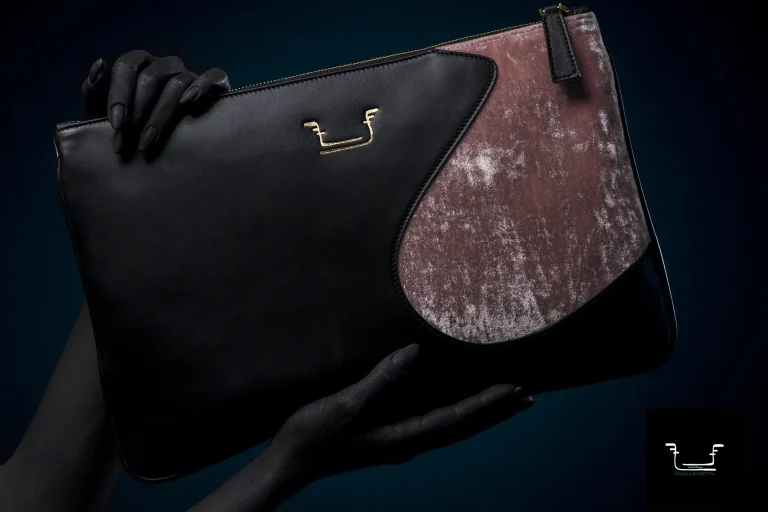 Borsa in pelle nera di Novella Rossettini con dettagli metallici, tenuta da mani dipinte di nero