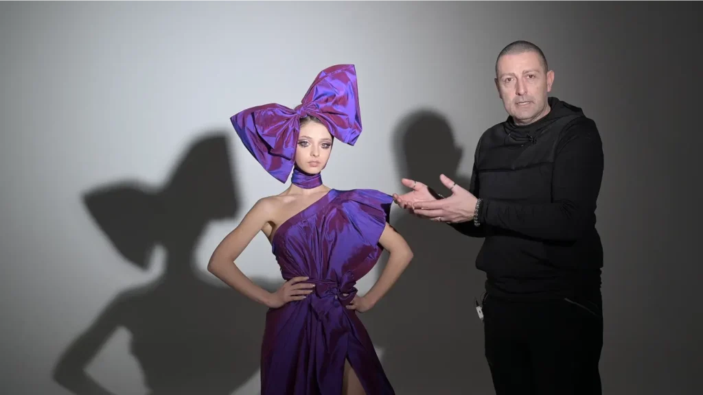 Francesco Francia con modella in abito viola durante una dimostrazione di illuminazione in studio.
