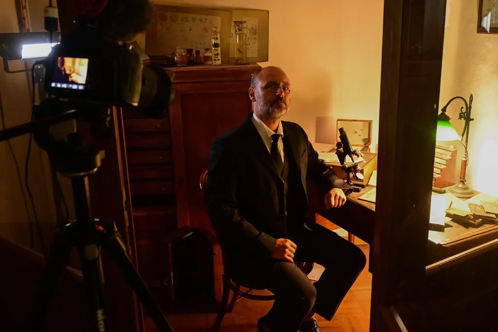 Francesco Francia durante le riprese di un video, seduto a una scrivania con un microscopio.